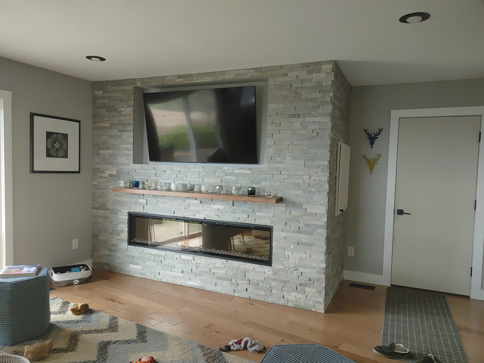 Modern see-through linear fireplace set in a light stacked-stone feature wall
